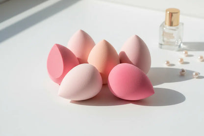 Makeup sponge set with 5 pink beauty blenders arranged on white surface for flawless foundation application